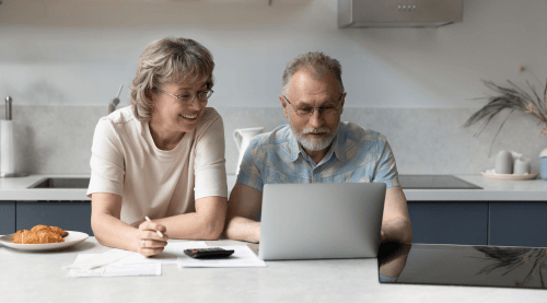 A senior couple browsing the internet for pre-retirement planning strategies through a laptop.